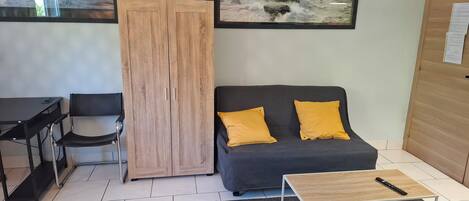 A modern living room with a dark sofa, wooden cabinet, and a framed seascape.