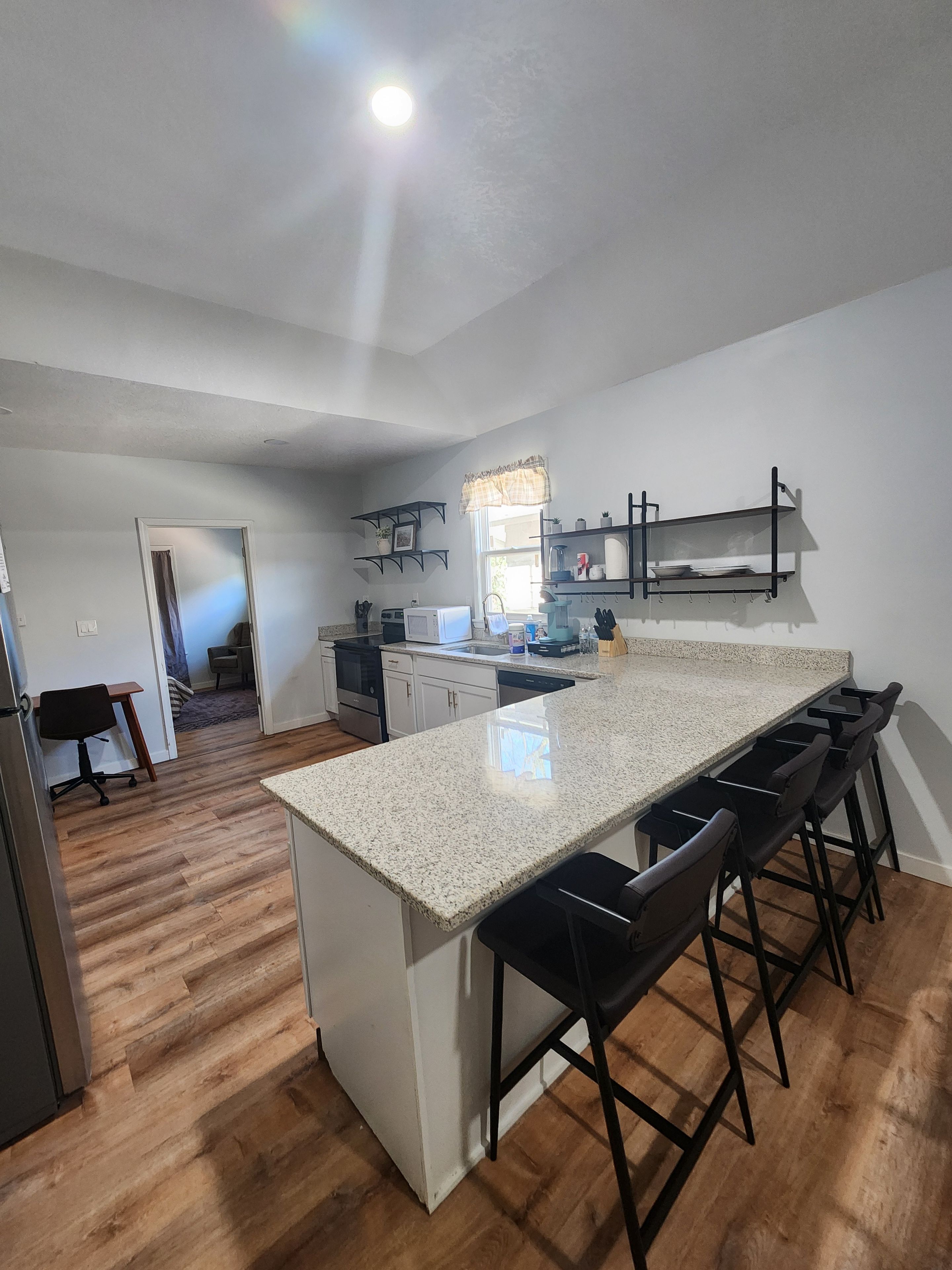A modern kitchen with a central island, bar stools, and built-in shelves.
