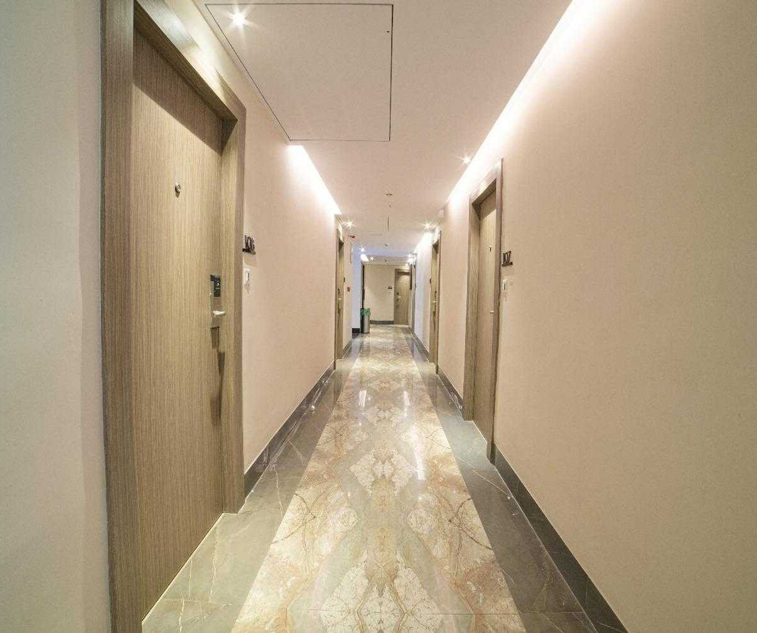 A hotel hallway with doors on both sides, a marble floor, and overhead lighting.