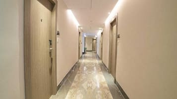 A hotel hallway with doors on both sides, a marble floor, and overhead lighting.