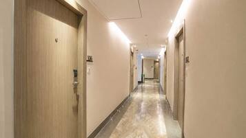 Een hotelgang met deuren met de nummers 106 en 107, een marmeren vloer en een plafond met inbouwverlichting.