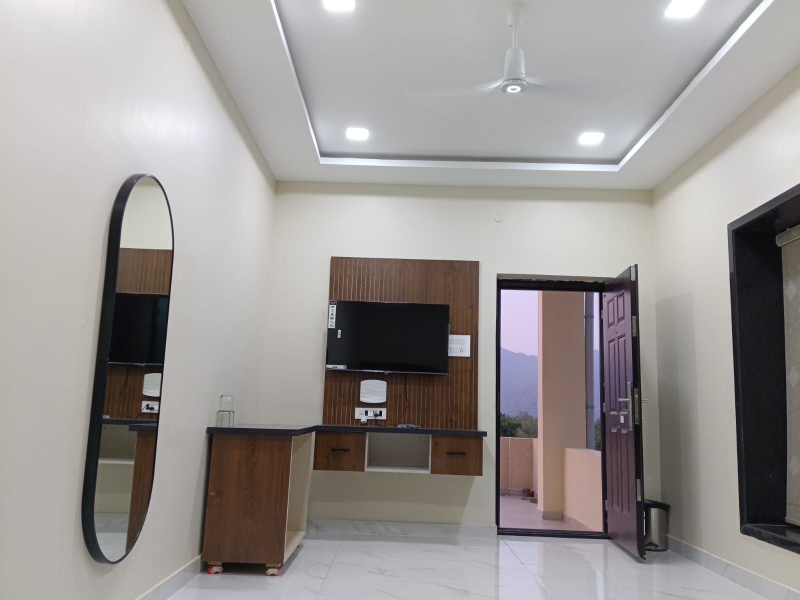 A modern bathroom with a mirror, vanity, and a flat-screen TV mounted on the wall.