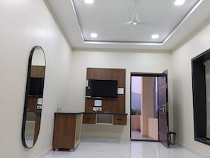 Un baño moderno con espejo, tocador y televisor de pantalla plana montado en la pared.