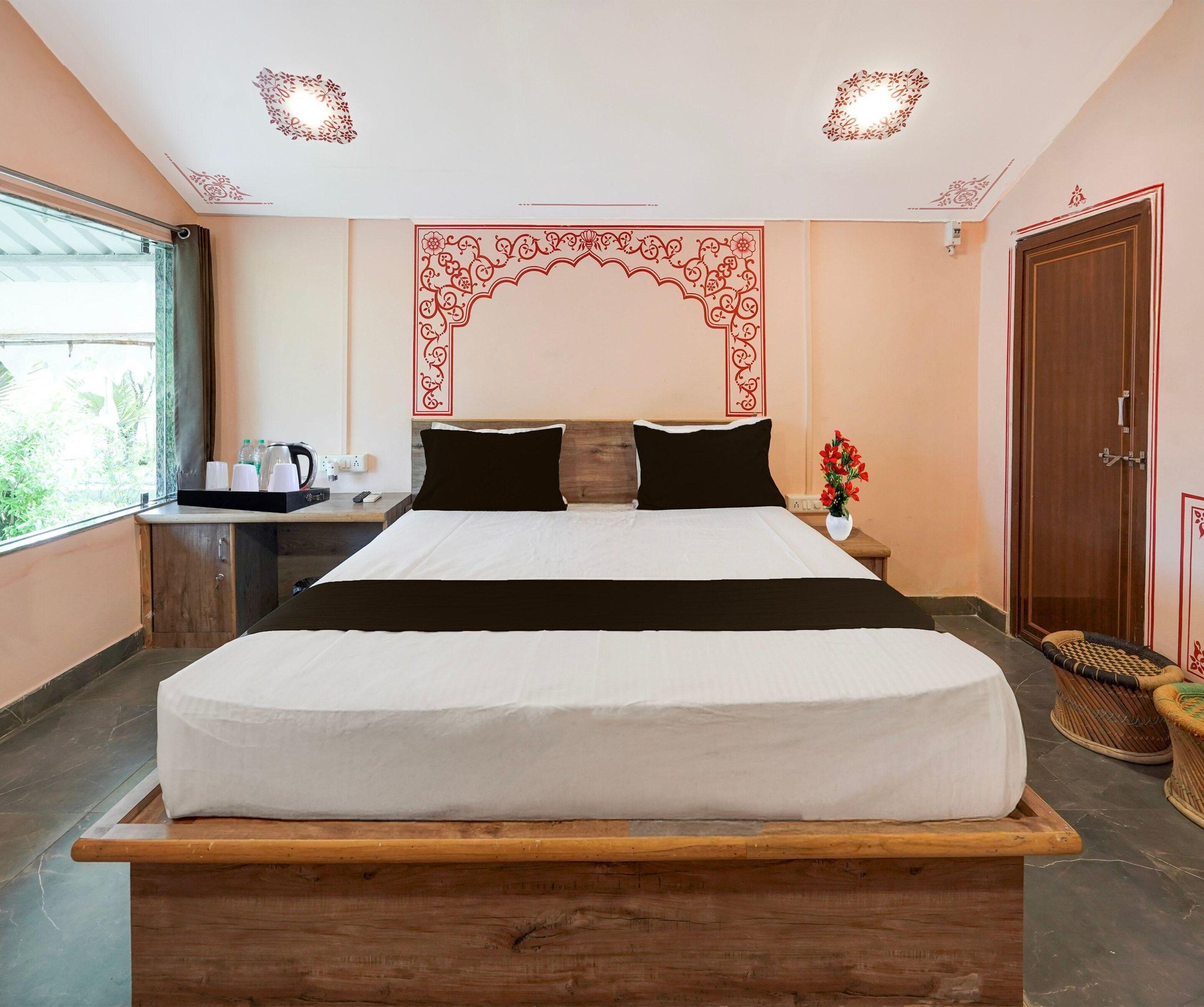 A hotel room with a bed, bedside table, and a window with a view.