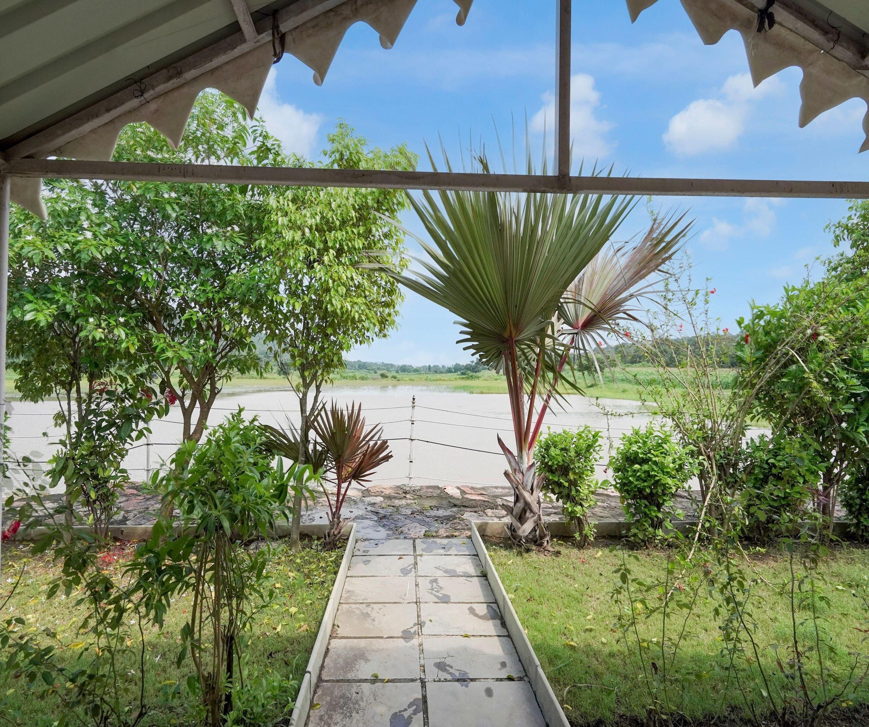 A covered walkway with a view of a water body and surrounding greenery.