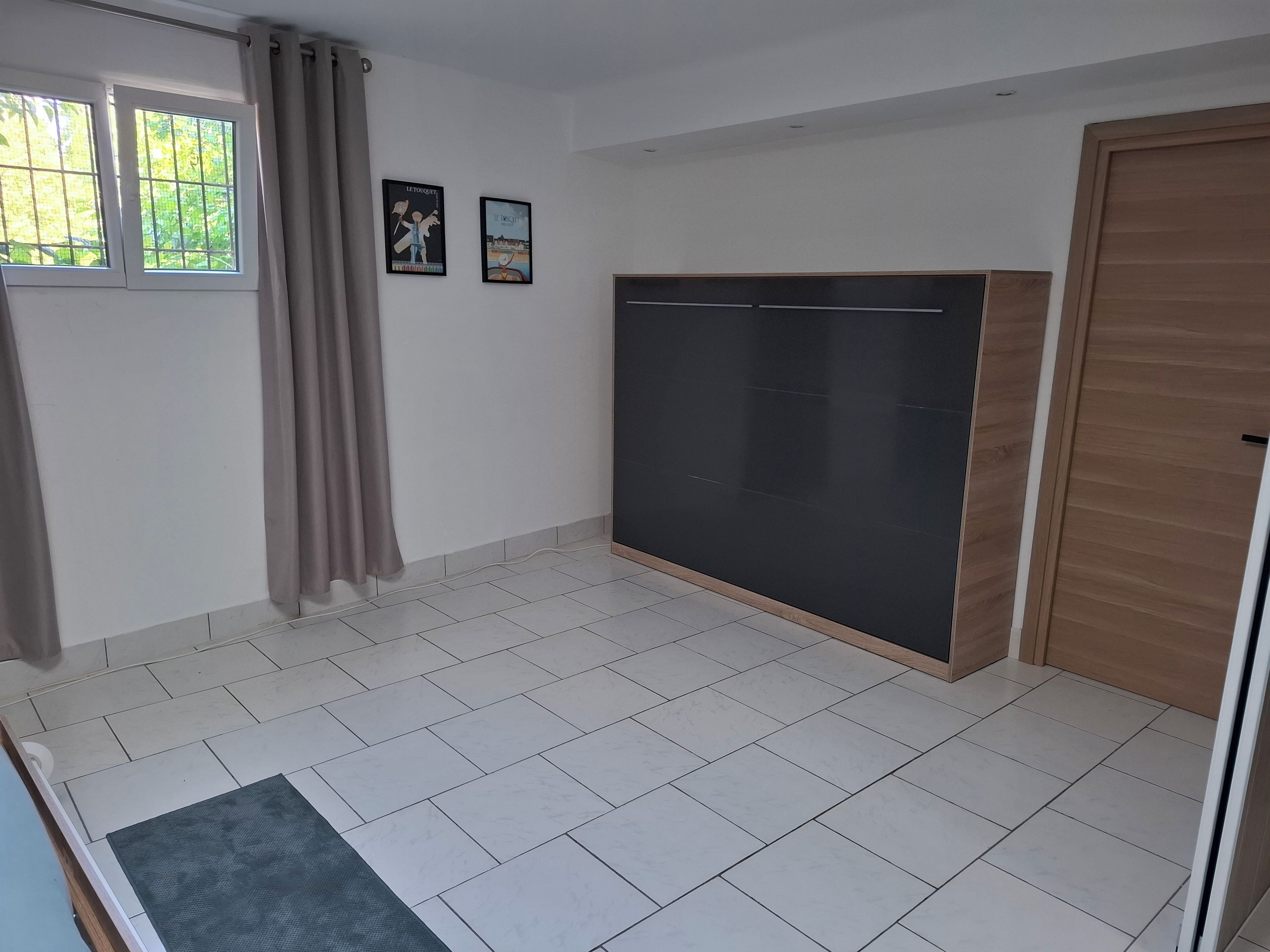 Een kamer met een ruime kledingkast, een raam met gordijnen en twee foto’s aan de muur.