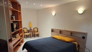 A bedroom with a bed, a desk, two chairs, and a shelf unit. - Vrbo Property (Seclin)