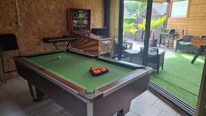 A pool table with a cue ball and red and yellow balls, a framed picture on the wall, and a view of an outdoor patio with furniture and a grill. - Vrbo Property (Seclin)