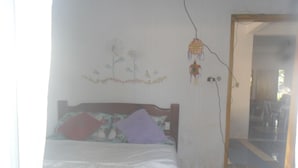 Quarto com cama, parede com painel floral e espelho.