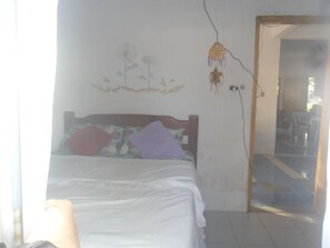 Un dormitorio con una cama, una pared con un mural floral y un espejo.