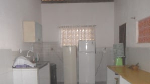 Cozinha com duas geladeiras, pia e piso revestido com azulejos.