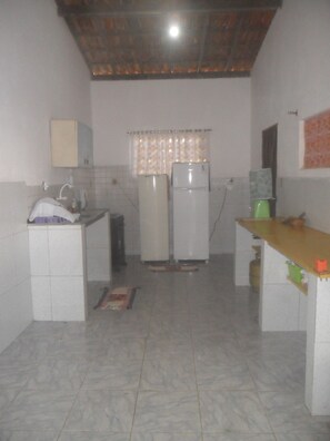 Una cocina con dos refrigeradores, un lavamanos y piso de baldosas.