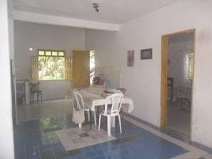 Un comedor con una mesa, sillas y una ventana con contraventanas abiertas.