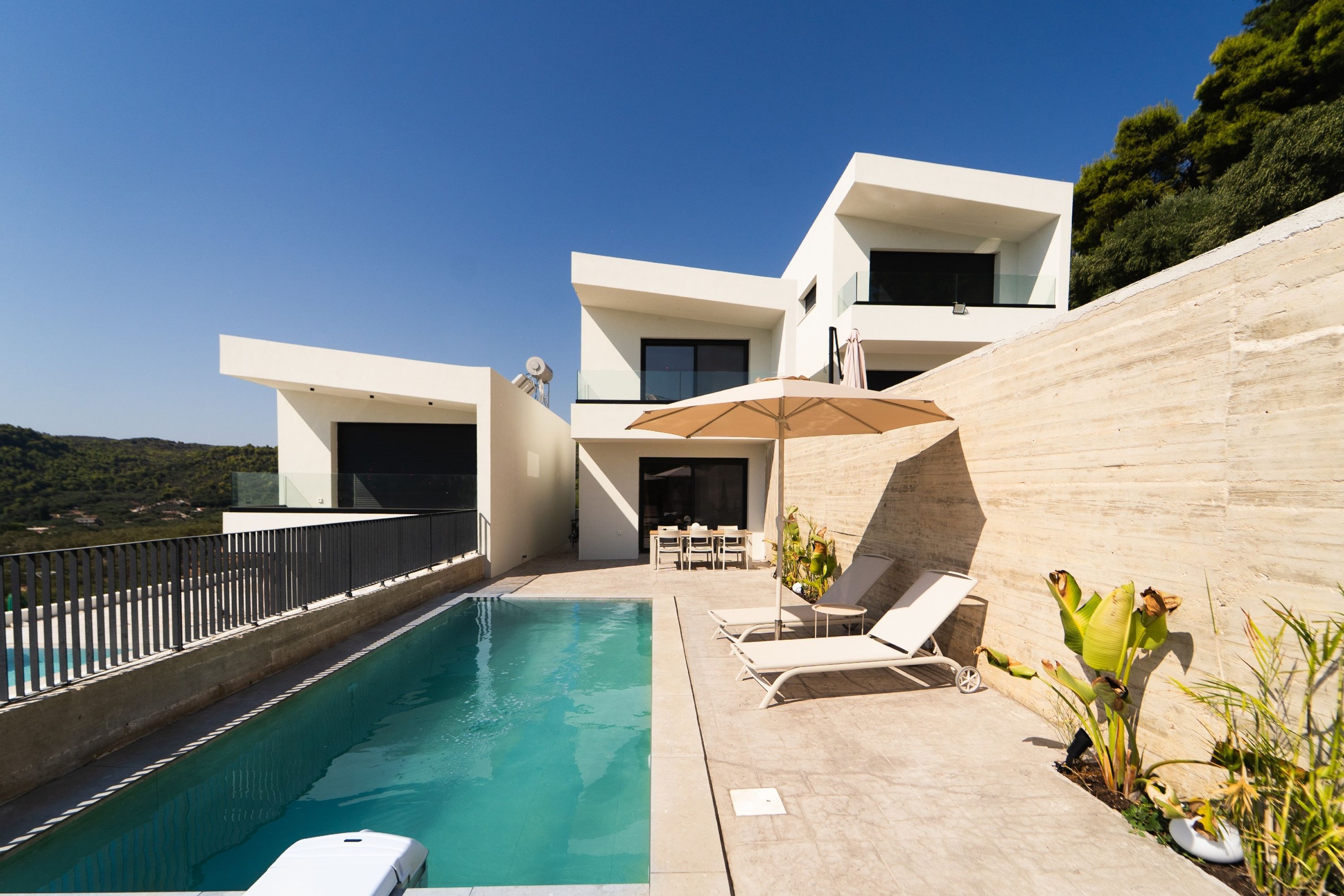 A modern house with a swimming pool, outdoor furniture, and a view of the landscape.