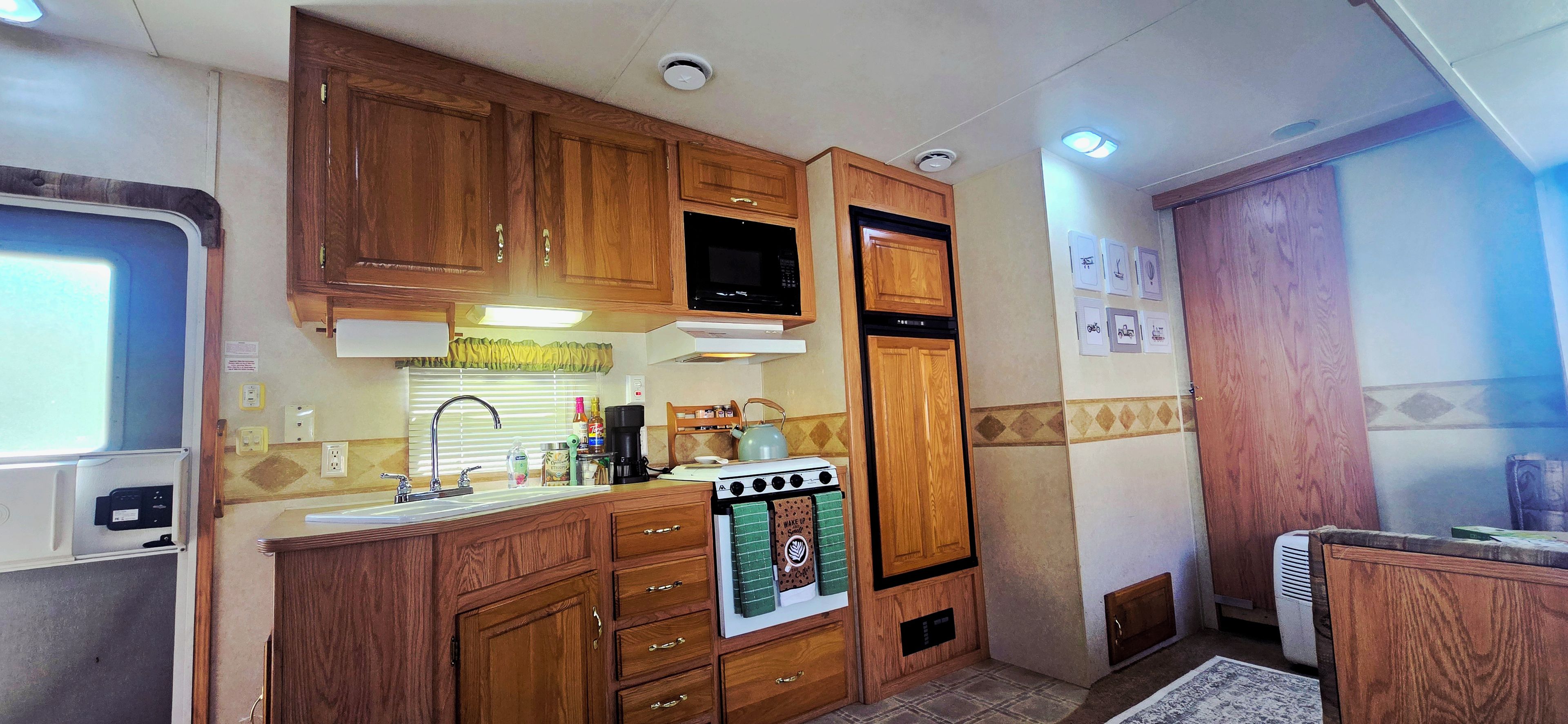 A compact kitchen with wooden cabinets, a microwave, a stove, and a sink.