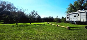 A grassy field with a wooden fence and a mobile home. - Serene 1-bedroom, 1-bathroom, 5th wheel with AC, farms next-door near Lucedale. (Lucedale)