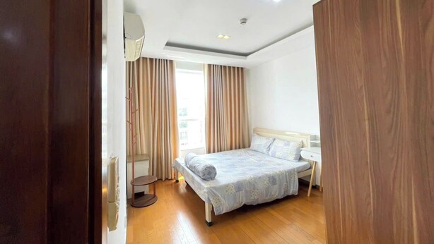A bedroom with a bed, a bedside table, a lamp, and a window with curtains. - EMERALD CELADON CITY 2PN2WC (Thanh pho Chi Minh)