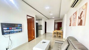 A modern living room with a flat-screen TV, a sofa, a coffee table, and a dining area with a table and chairs. - EMERALD CELADON CITY 2PN2WC (Thanh pho Chi Minh)