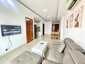 A modern living room with a flat-screen TV, a sofa, a coffee table, and a dining area with a table and chairs. - EMERALD CELADON CITY 2PN2WC (Thanh pho Chi Minh)