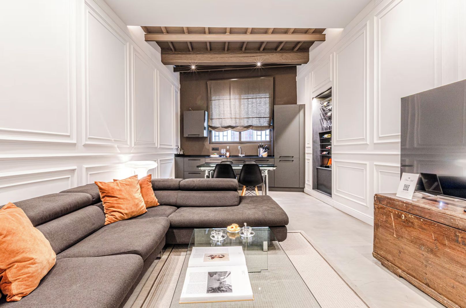 A modern living room with a sectional sofa, a coffee table, and a television on a wooden cabinet.