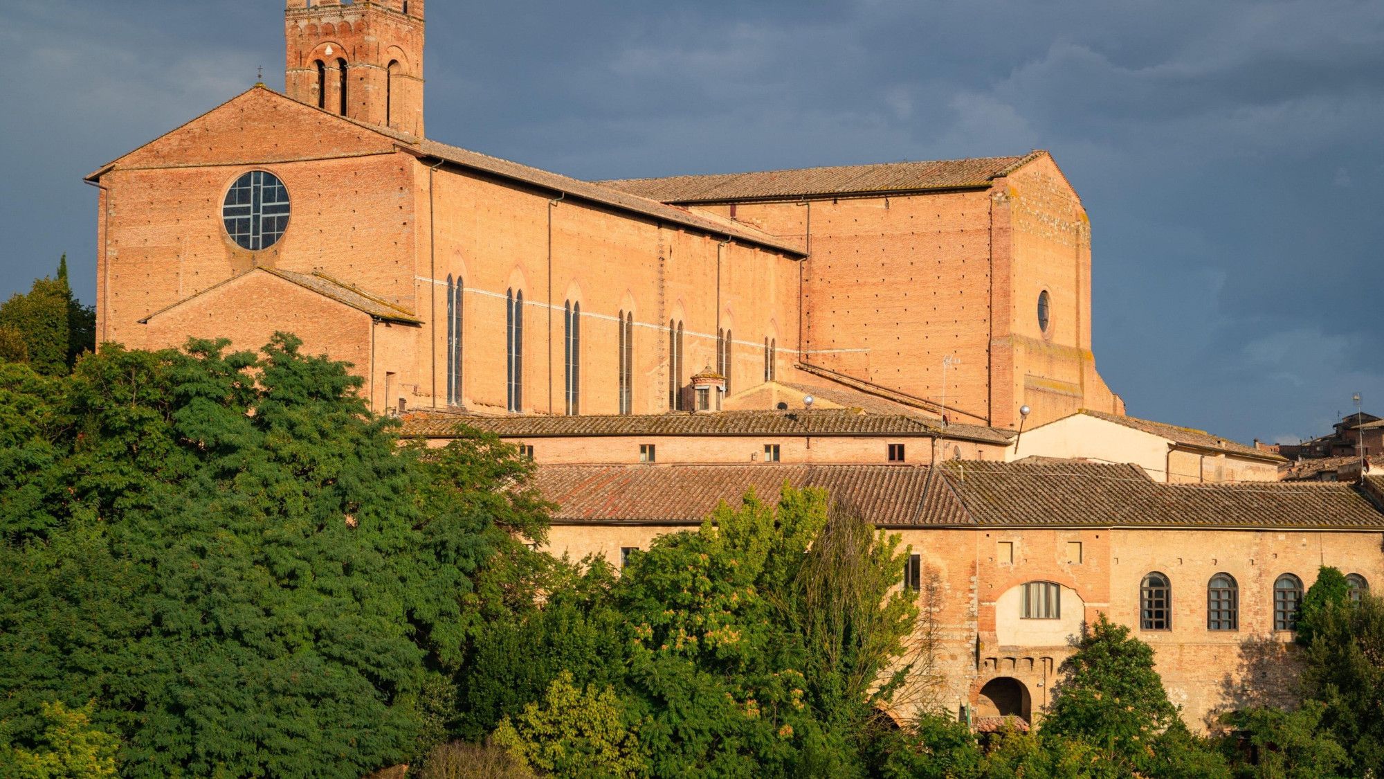 A large brick building with a prominent bell tower and a circular window.