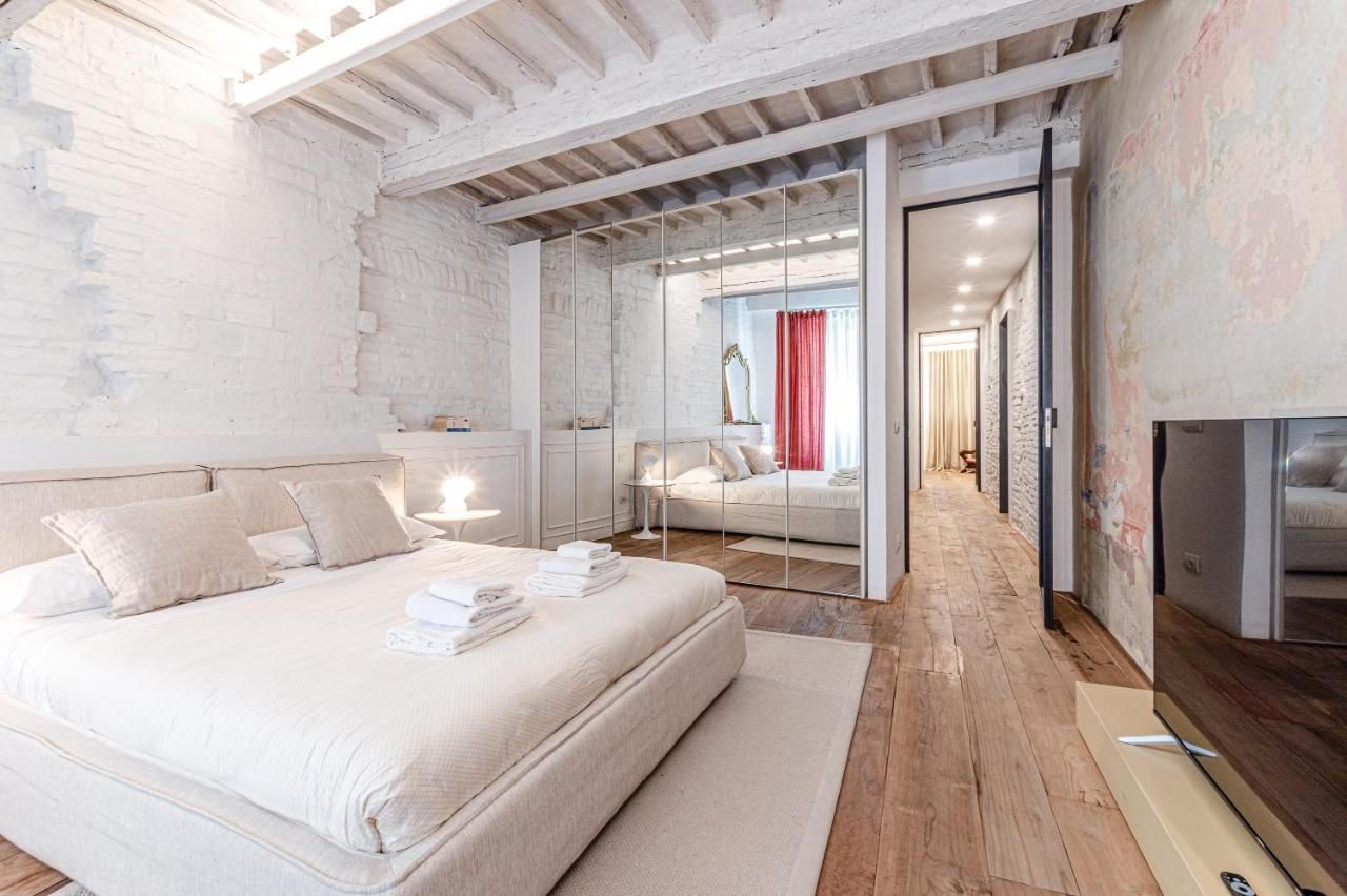 Une chambre moderne avec un grand lit, un dressing et une vue sur une autre pièce.