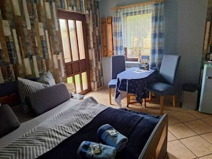 A room with a bed, a small table, and a chair. There is a window with curtains, and a door is visible. - Vacation at Umlauf (Heringsdorf)