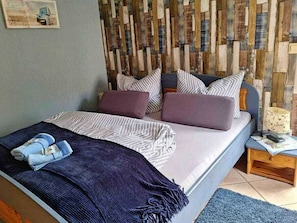 A bedroom with a bed, pillows, a blanket, a nightstand, and a lamp. - Vacation at Umlauf (Heringsdorf)