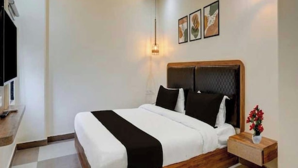 Una habitación de hotel con cama, mesita de noche y lámpara de pared.