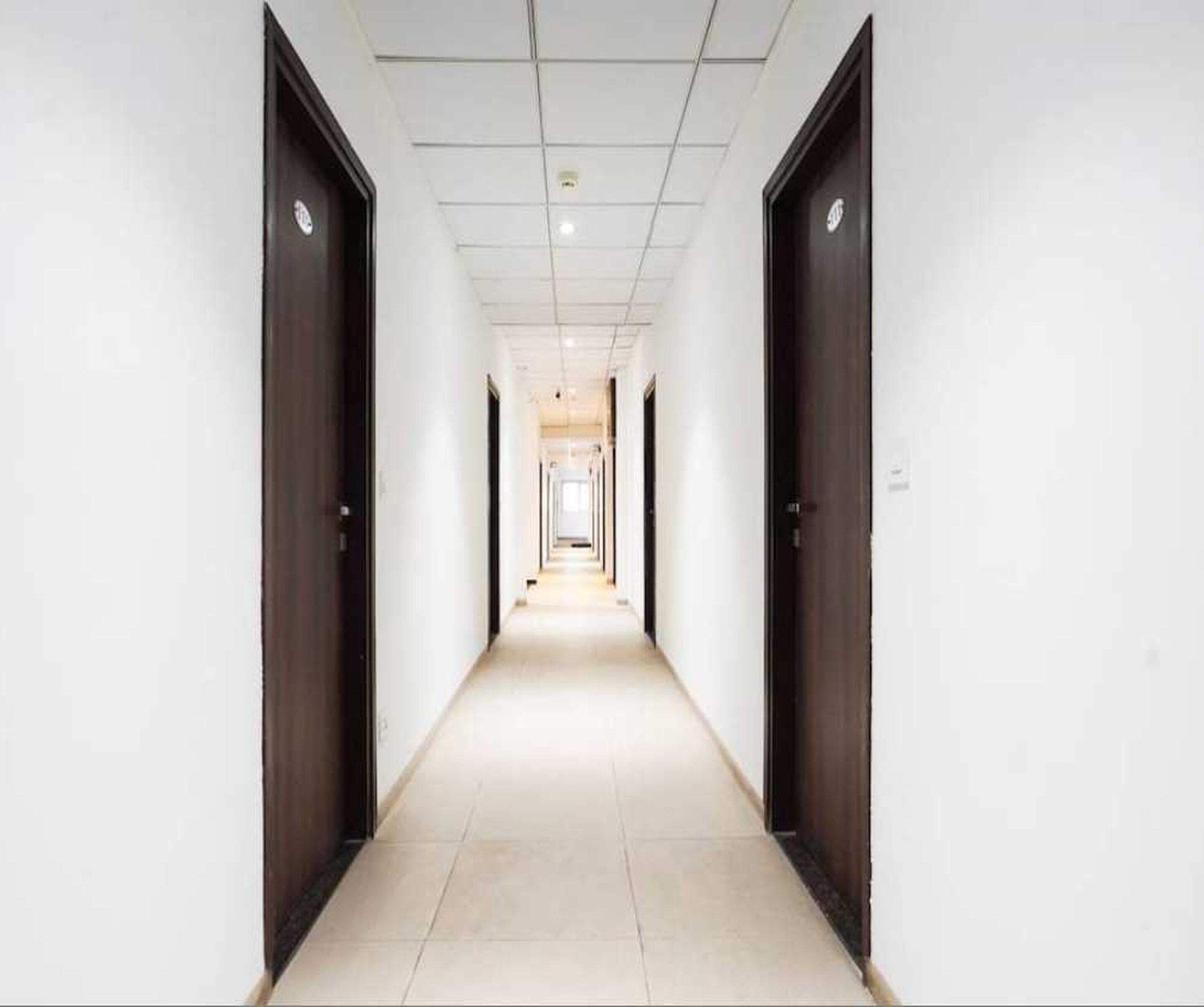 A corridor with doors on both sides, leading to a bright room at the end.