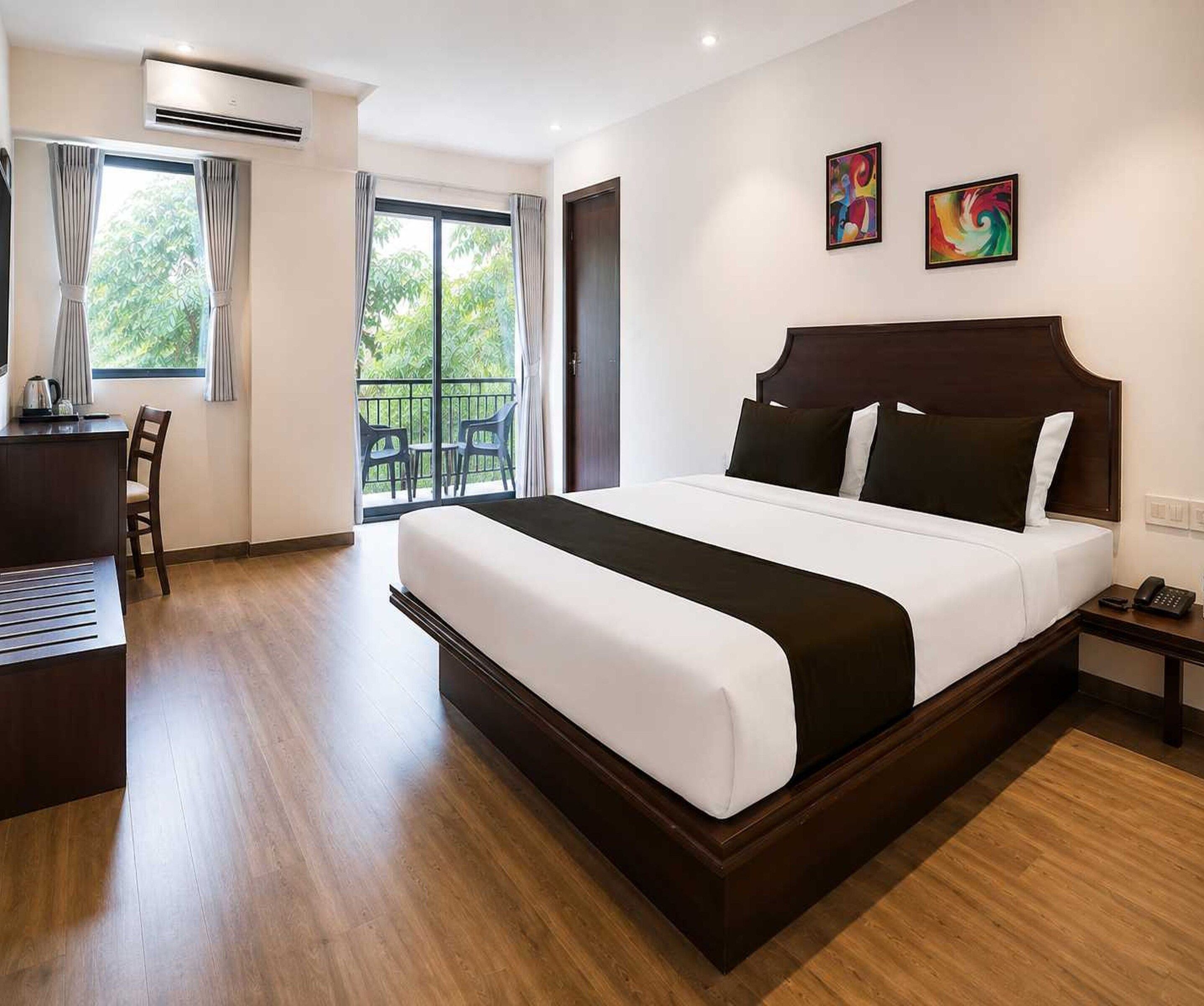 Ein Hotelzimmer mit einem großen Bett, einem Schreibtisch und einem Balkon mit Sitzgelegenheiten.