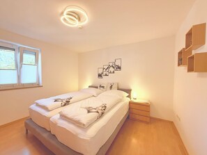 Ett sovrum med en säng, sängbord, en väggmonterad lampa och konstverk.