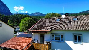 Un edificio residencial con techo de tejas, antena parabólica y vistas a un paisaje montañoso.