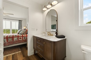 Un dormitorio con cama, mesita de noche, cómoda, espejo y ventana.