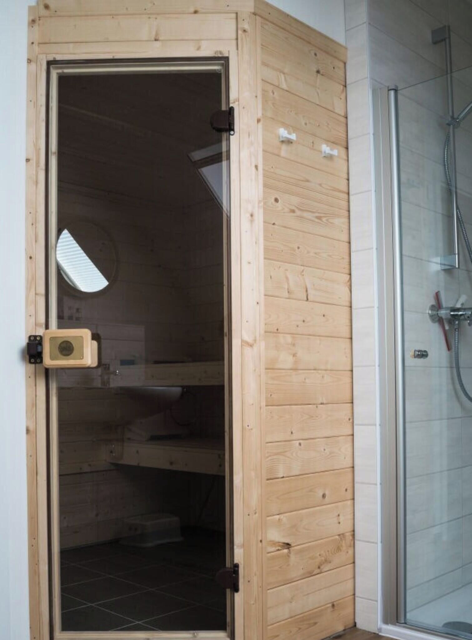 A wooden room with a glass door leading to a shower area.