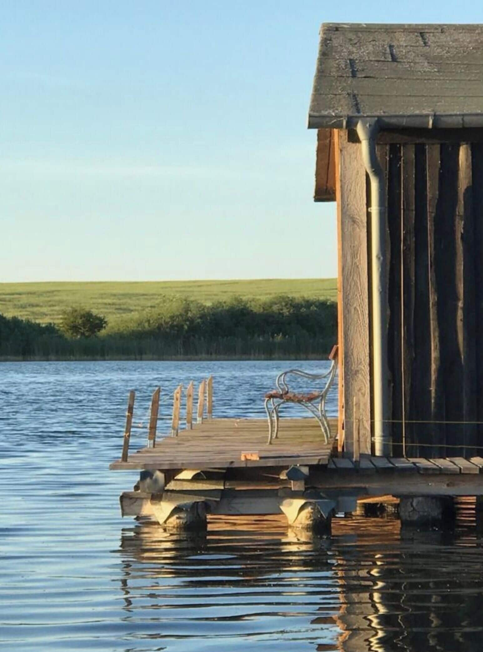 A wooden dock extending into a body of water with a chair on it.