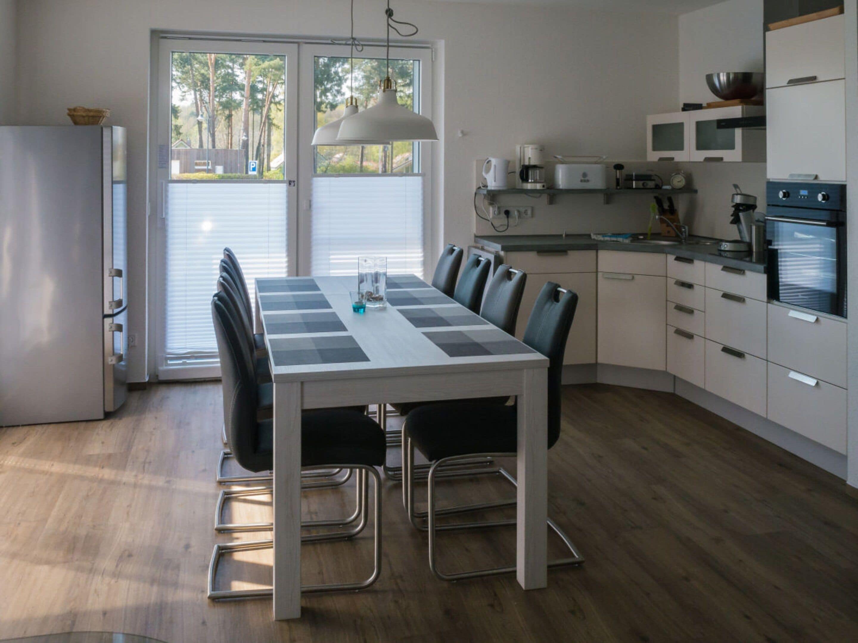 Een moderne keuken met een eettafel, stoelen en een inbouwoven.
