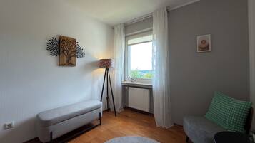 Quarto com um banco, luminária de chão, sofá e vista pela janela.