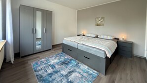 Quarto com cama, mesas de cabeceira, guarda-roupa e tapete.