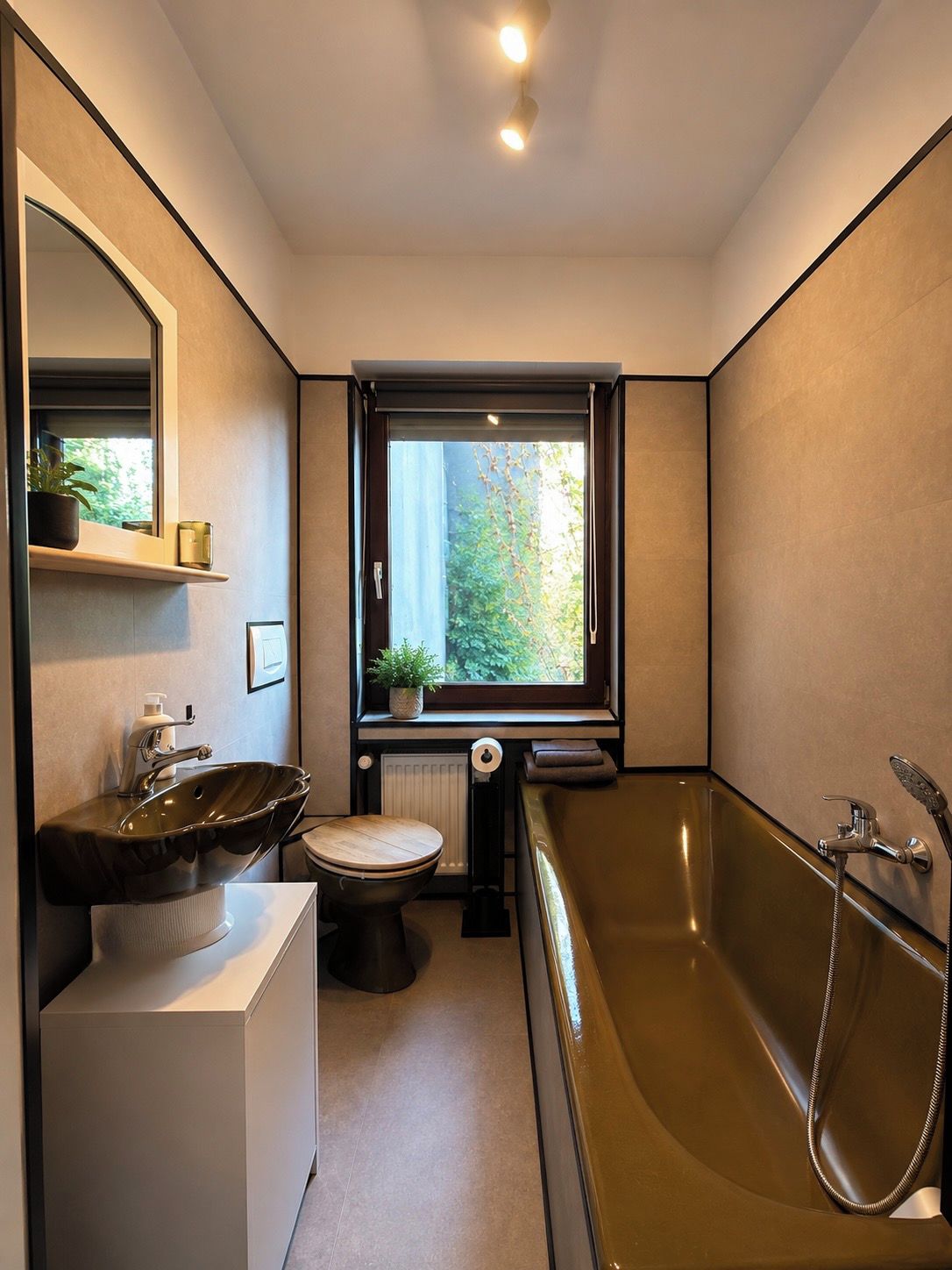 Ein modernes Badezimmer mit Badewanne, Waschbecken, Toilette und Fenster.
