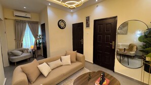 A living room with a sofa, coffee table, and a round mirror. - Haven 21;  Luxury 1-Bedroom Serviced Apartment in Ajah (Close)