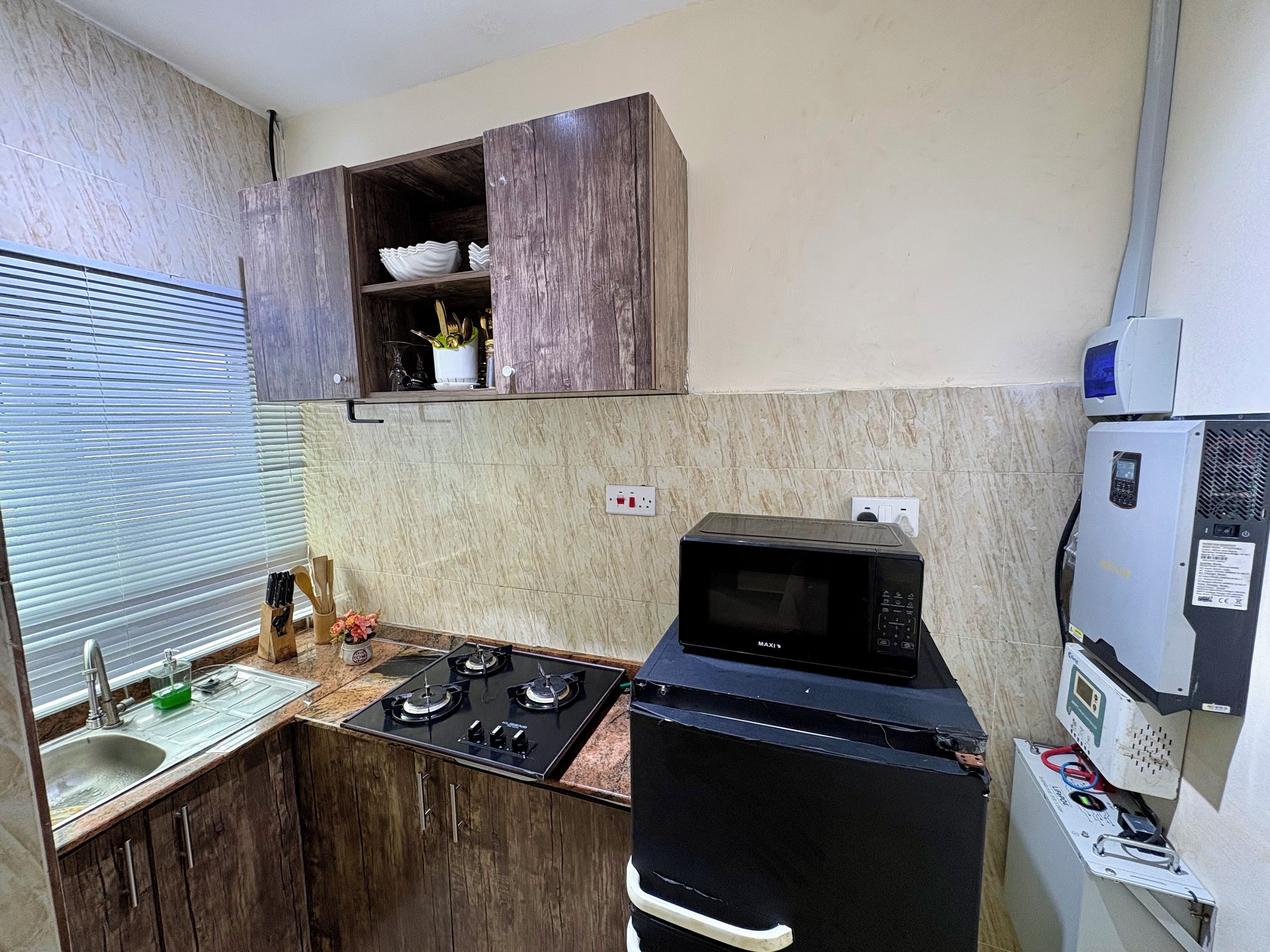 A compact kitchen with a gas stove, a microwave, wooden cabinets, and a small countertop.