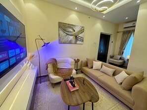 Un saló modern amb televisió plana, un sofà, una taula de centre i un quadre a la paret.