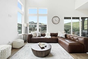 Ein modernes Wohnzimmer mit einem braunen Ledersofa, einem runden Couchtisch und einer großen Wanduhr.