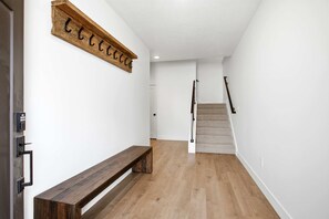 A hallway with a wooden bench, a staircase, and a wall-mounted sign. - 4 Bedroom Deer Valley East Townhome (Hideout)