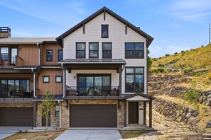 A multi-story residential building with a garage, a covered patio, and a stone retaining wall. - 4 Bedroom Deer Valley East Townhome (Hideout)