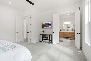 A modern bedroom with a bed, a desk with a chair, and a bathroom with a sink and mirror. - 4 Bedroom Deer Valley East Townhome (Hideout)