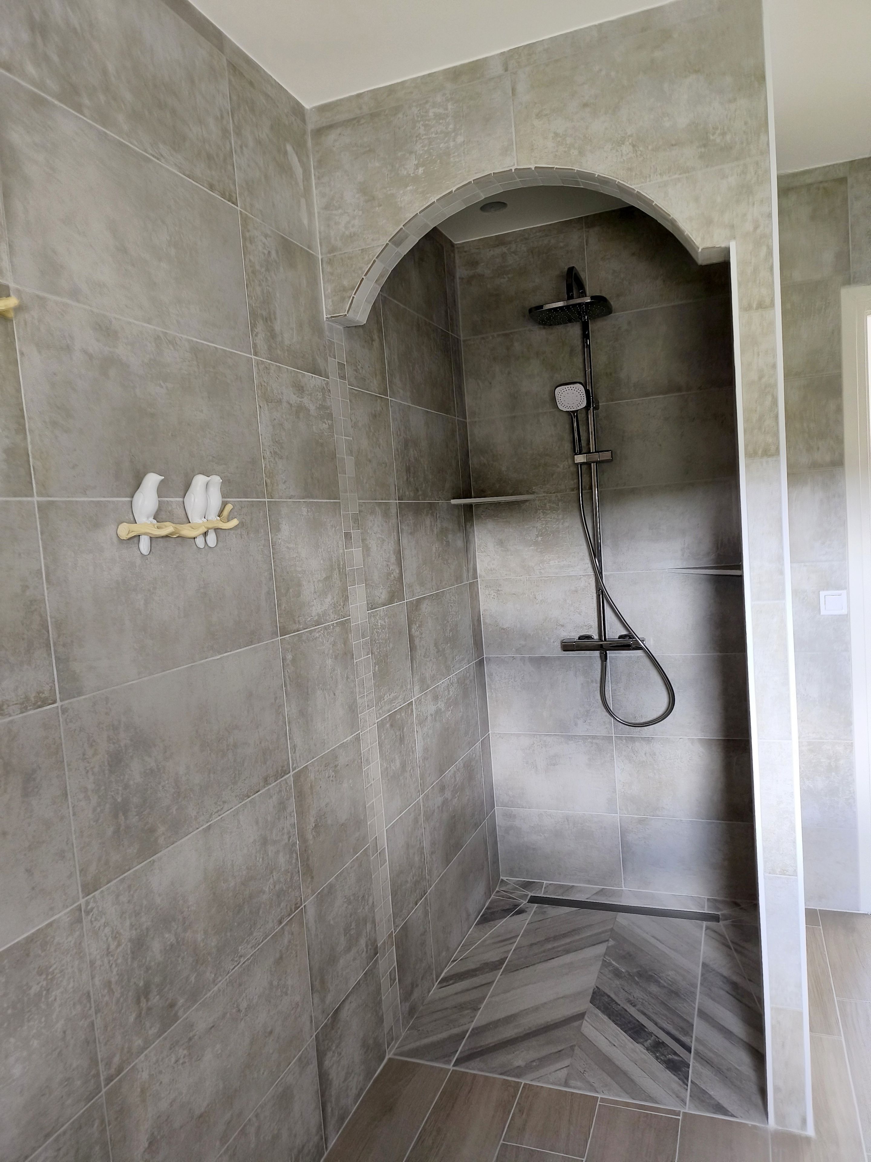 A shower area with a curved wall, tiled floor, and a showerhead.