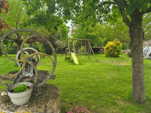 A garden with a swing set, a rusty metal sculpture, and a potted plant. - La Plume Blanche - Refuge idéal : piscine, détente et moments précieux (Mailhoc)