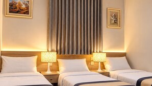 A hotel room with three beds, a large window with curtains, and two wall-mounted lamps. - Sakab Al Aseel Hotel  (Makkah)